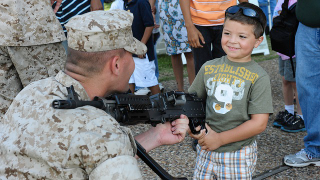 Illustration for article titled For Some Reason, Adorable Kids Are Holding Big Ass Guns